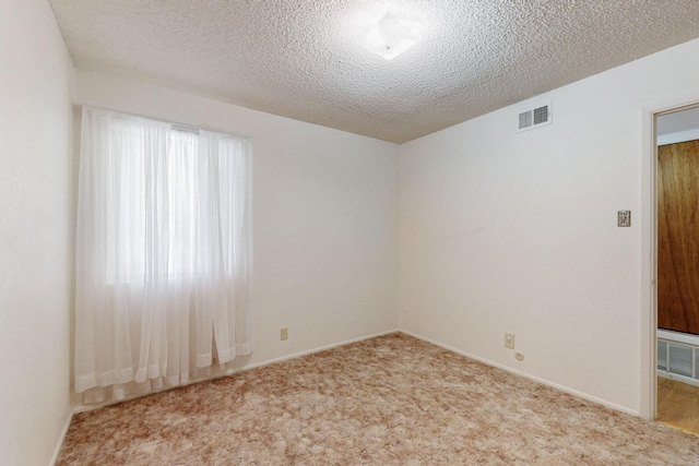 carpeted spare room featuring visible vents and a textured ceiling