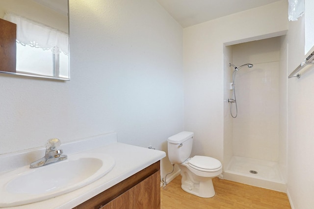 full bath with toilet, a tile shower, wood finished floors, and vanity