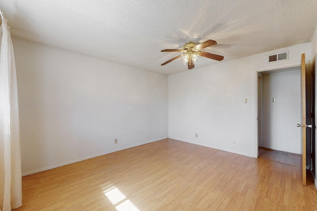 spare room with visible vents, light wood-style floors, ceiling fan, a textured ceiling, and baseboards