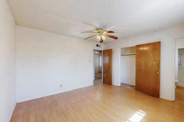 unfurnished bedroom with a textured ceiling, light wood finished floors, a closet, and visible vents