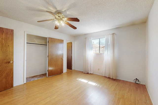 unfurnished bedroom featuring a closet, ceiling fan, light wood-style flooring, and a textured ceiling