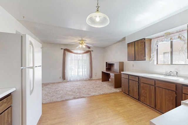 kitchen with light wood-style flooring, light carpet, a sink, light countertops, and freestanding refrigerator