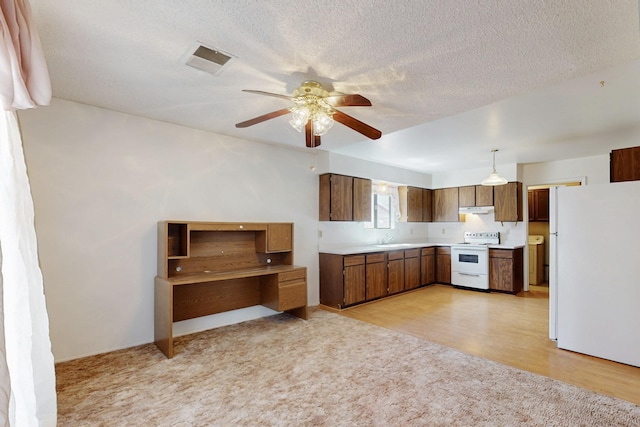 kitchen featuring under cabinet range hood, white appliances, a sink, visible vents, and light countertops