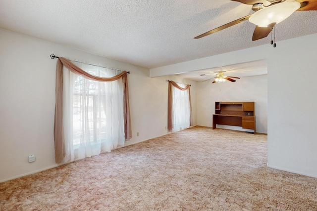 carpeted empty room with a ceiling fan, a wealth of natural light, and a textured ceiling