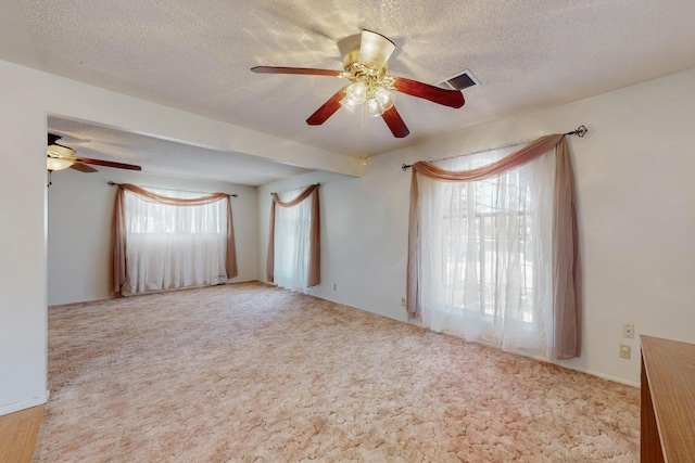 carpeted spare room with visible vents and a textured ceiling