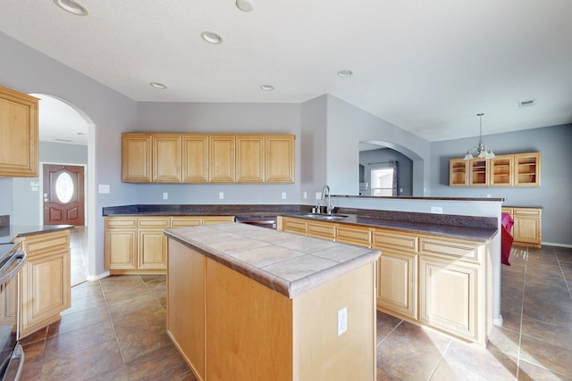 kitchen featuring a kitchen island, a peninsula, light brown cabinetry, a sink, and recessed lighting