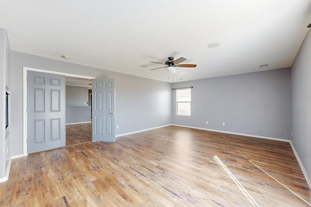 empty room featuring light wood finished floors, baseboards, and a ceiling fan