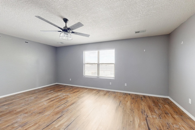 spare room featuring wood finished floors, visible vents, and baseboards