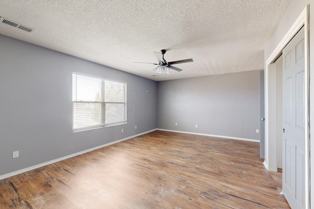 unfurnished bedroom featuring visible vents, baseboards, light wood-style flooring, ceiling fan, and a textured ceiling