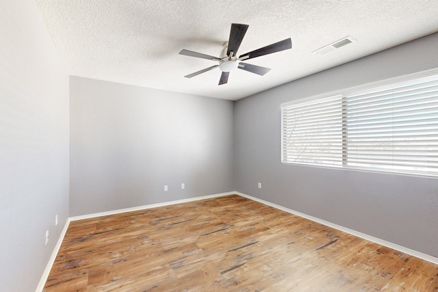 unfurnished room with visible vents, ceiling fan, a textured ceiling, wood finished floors, and baseboards