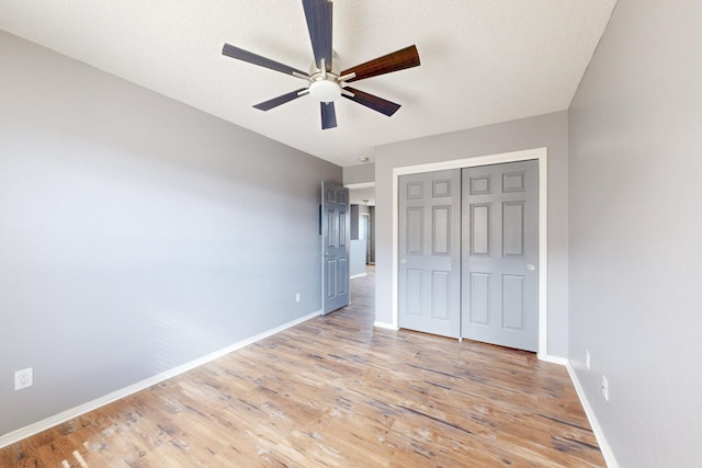 unfurnished bedroom featuring light wood finished floors, a closet, a ceiling fan, and baseboards