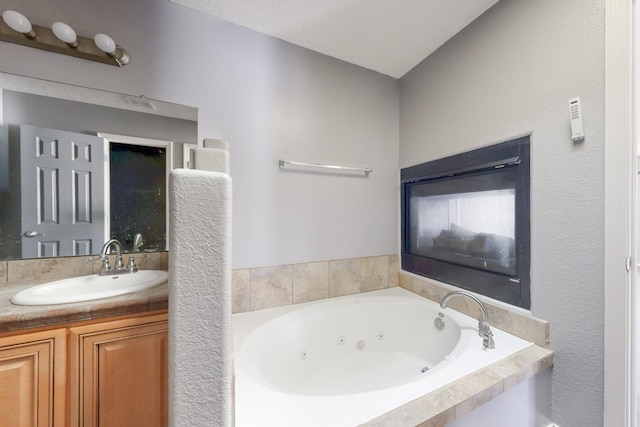 full bath with vanity and a tub with jets