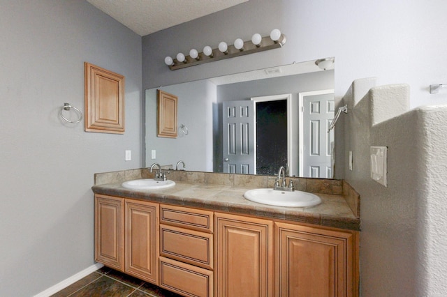 bathroom with double vanity, tile patterned flooring, baseboards, and a sink