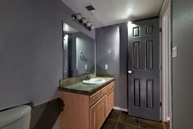 half bathroom featuring visible vents, vanity, tile patterned flooring, and toilet