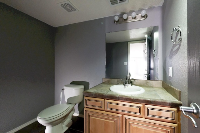 bathroom featuring baseboards, visible vents, vanity, and toilet