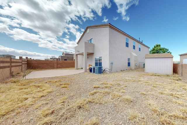 back of property with a patio, stucco siding, a shed, a fenced backyard, and an outdoor structure