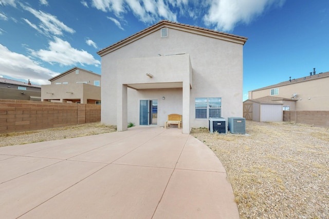 back of property featuring a storage shed, fence, central AC, and stucco siding