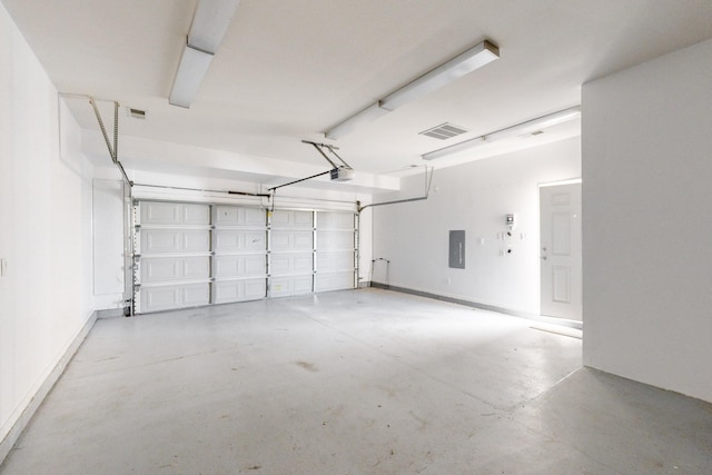 garage featuring a garage door opener, electric panel, and visible vents