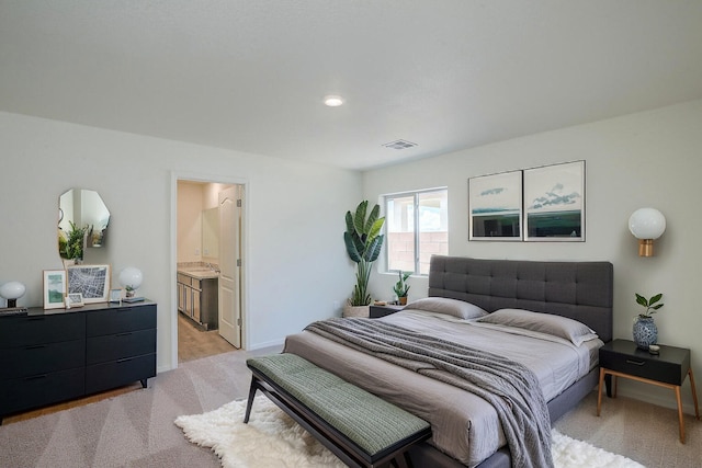 bedroom with baseboards, visible vents, connected bathroom, and light colored carpet