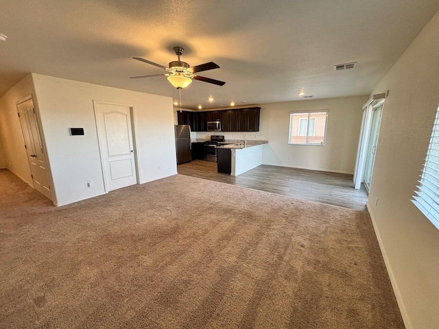 unfurnished living room featuring visible vents, carpet flooring, ceiling fan, a textured ceiling, and baseboards