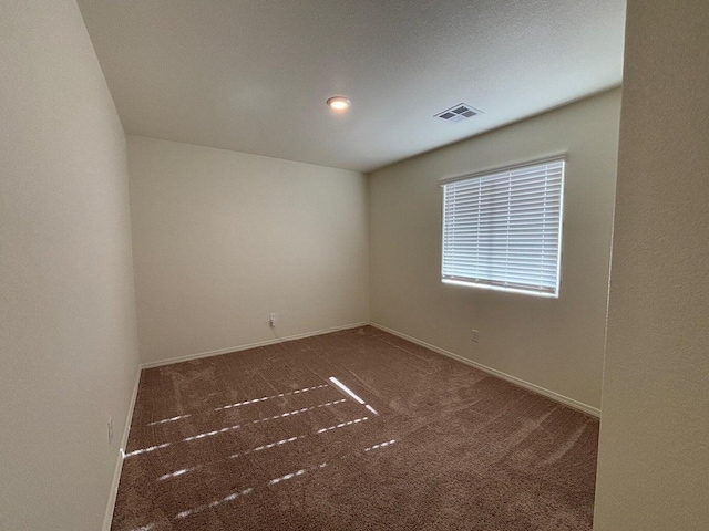 carpeted spare room featuring visible vents and baseboards