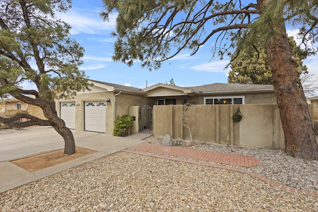 view of front of property with a fenced front yard, concrete driveway, a garage, and stucco siding