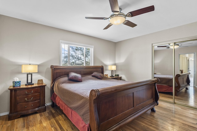 bedroom featuring ceiling fan, a closet, baseboards, and wood finished floors