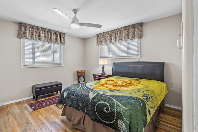 bedroom with ceiling fan, wood finished floors, and baseboards