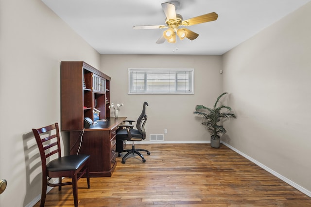 office area featuring a ceiling fan, visible vents, baseboards, and wood finished floors