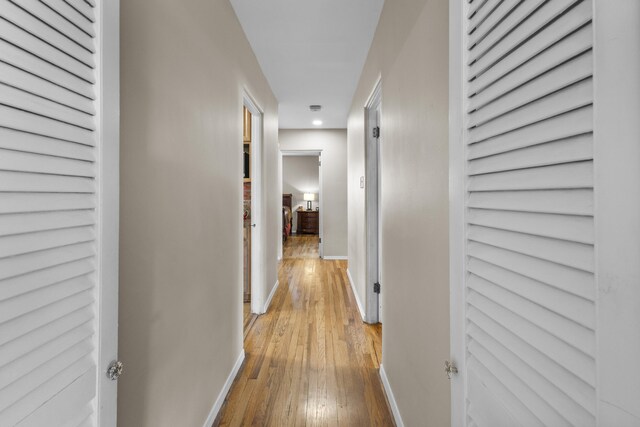 hall featuring light wood-style flooring and baseboards