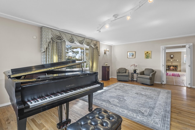 sitting room with a fireplace, baseboards, track lighting, and wood finished floors