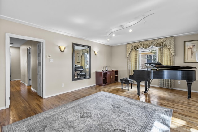 sitting room featuring wood finished floors, rail lighting, and baseboards