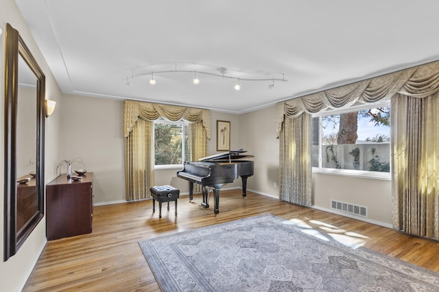 sitting room featuring light wood finished floors, track lighting, visible vents, and baseboards