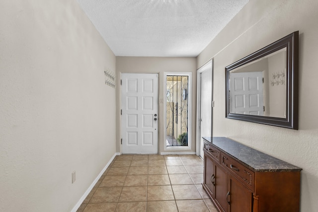 foyer entrance with a textured ceiling, baseboards, and light tile patterned floors