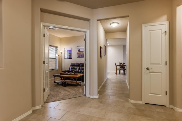 hallway with light tile patterned floors, light carpet, and baseboards