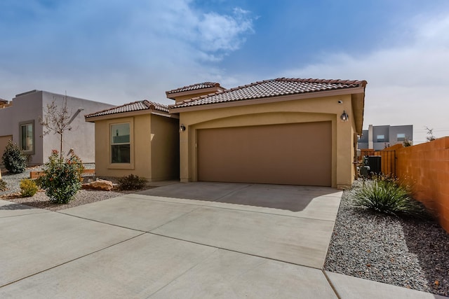 mediterranean / spanish-style house with concrete driveway, fence, an attached garage, and stucco siding