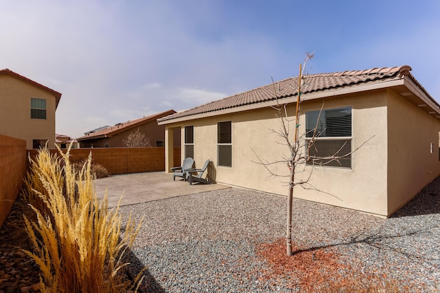 back of house with a tiled roof, a patio area, a fenced backyard, and stucco siding