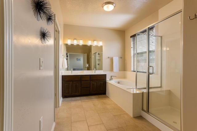 full bathroom featuring double vanity, a stall shower, a garden tub, a textured ceiling, and a sink