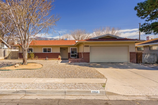 single story home with brick siding, an attached garage, driveway, and fence