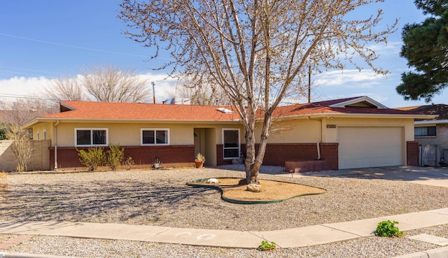 ranch-style home featuring stucco siding, driveway, fence, an attached garage, and brick siding