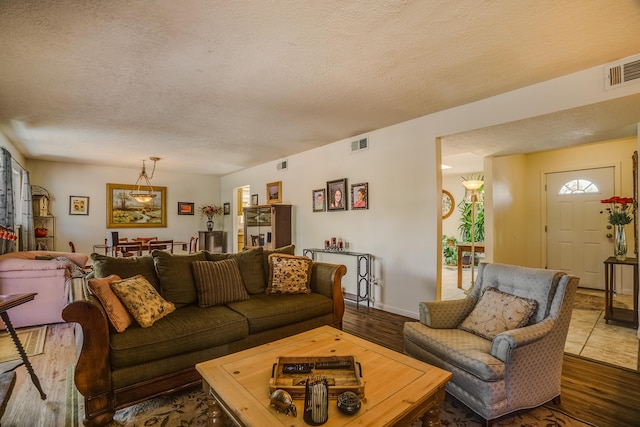 living area featuring visible vents, a textured ceiling, and wood finished floors