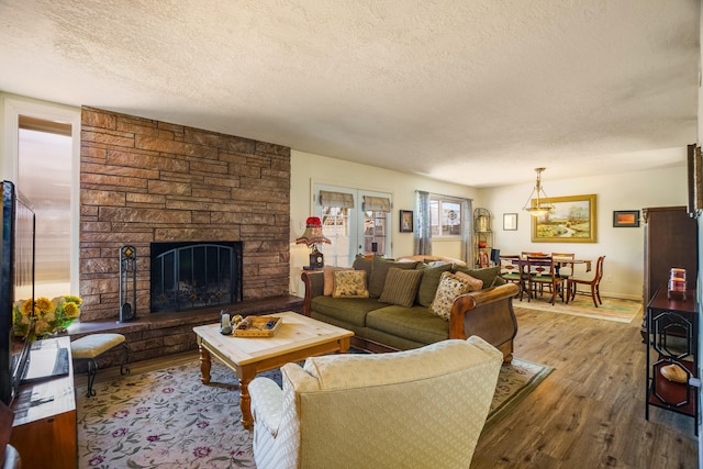 living area featuring a fireplace, a textured ceiling, and wood finished floors