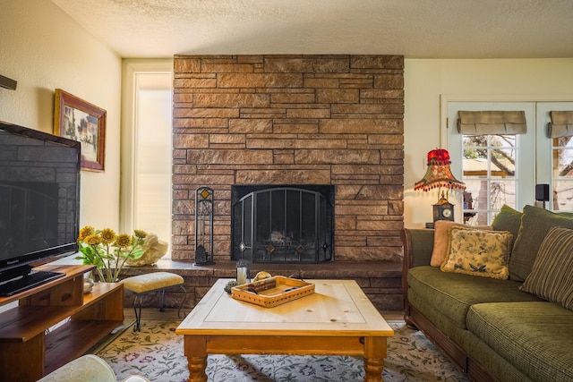 living area featuring a textured ceiling and a stone fireplace