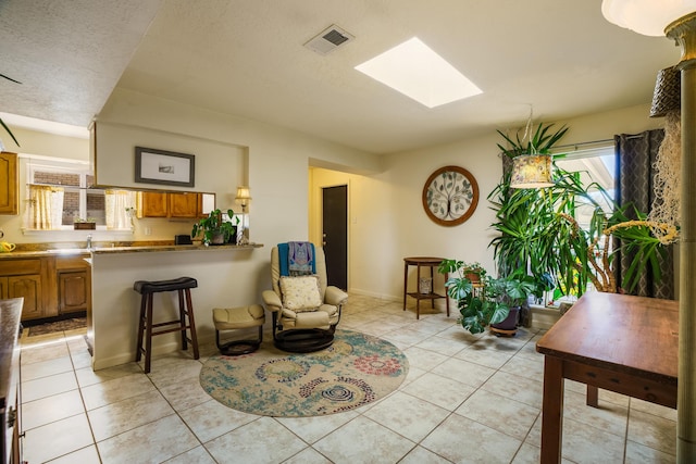 sitting room featuring light tile patterned floors, visible vents, a textured ceiling, and a skylight