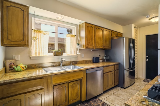 kitchen with a sink, light tile patterned floors, brown cabinetry, and stainless steel appliances