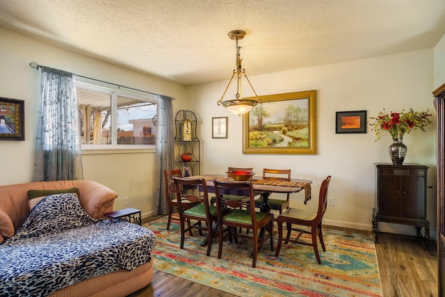 dining space featuring wood finished floors, baseboards, and a textured ceiling