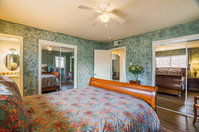 bedroom featuring visible vents, a textured ceiling, wood finished floors, wallpapered walls, and ceiling fan