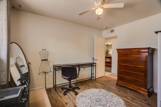 office featuring visible vents, a ceiling fan, a textured ceiling, wood finished floors, and baseboards