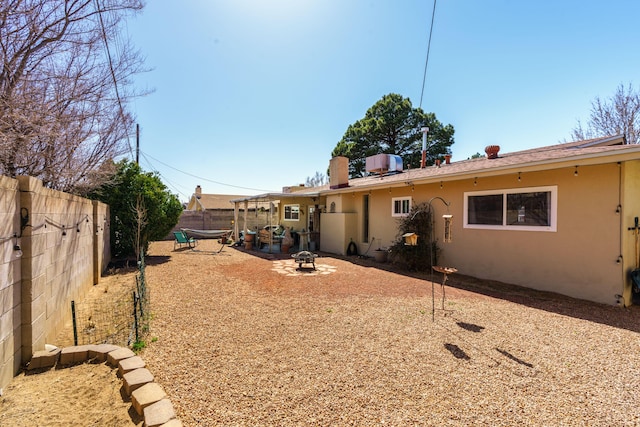 rear view of property with stucco siding, a patio, a fire pit, and a fenced backyard