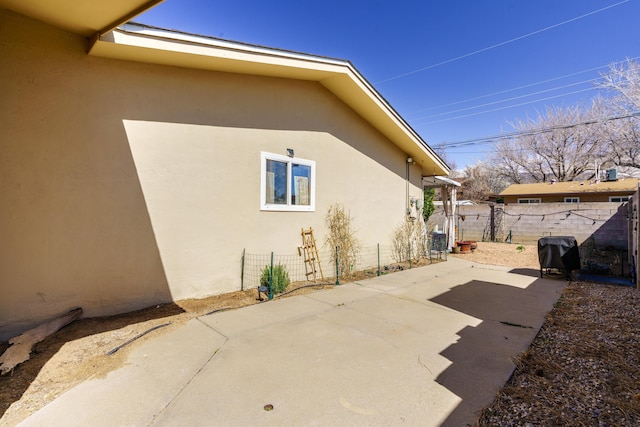 view of property exterior with a patio area, stucco siding, and fence